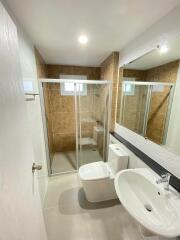 Modern bathroom with clear glass shower enclosure, large mirror, and stylish tiling