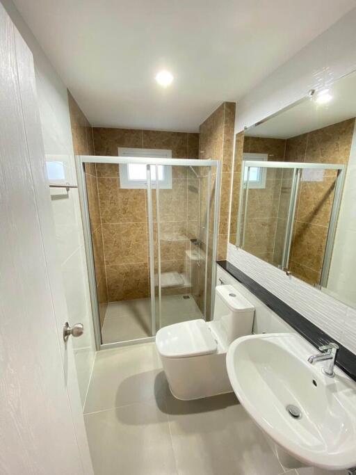 Modern bathroom with clear glass shower enclosure, large mirror, and stylish tiling