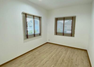 Spacious and bright empty bedroom with hardwood floors and open blinds