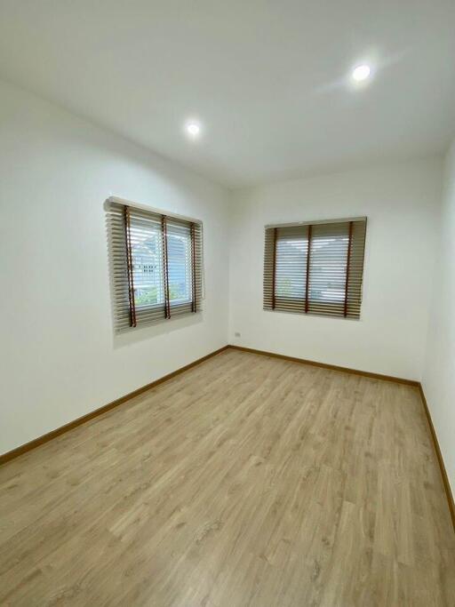 Spacious and bright empty bedroom with hardwood floors and open blinds