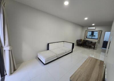 Spacious and modern living room with bright lighting, tiled flooring, and comfortable seating