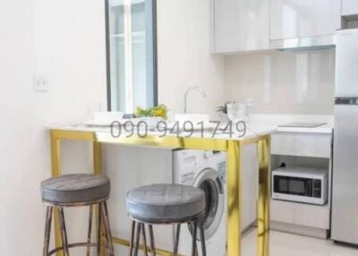 Modern kitchen with breakfast bar, appliances, and laundry facilities