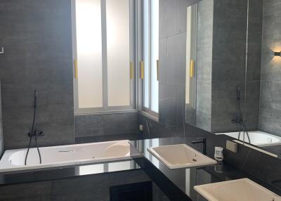 Modern bathroom with dual sinks, large bathtub, and gray tile design