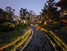 Twilight view of a landscaped pathway leading to modern residential buildings
