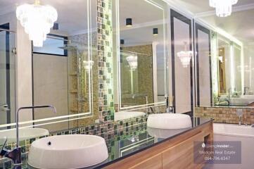 Modern bathroom with dual vessel sinks and decorative tiled wall
