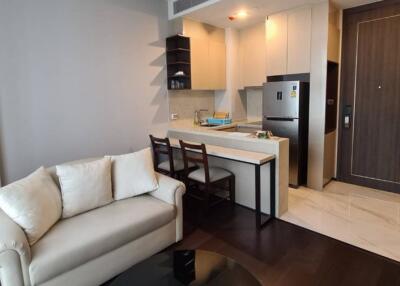 Open plan living room with adjoining kitchen space featuring modern appliances and a comfortable sofa