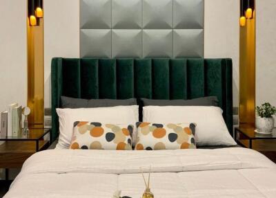 Modern bedroom with a large green upholstered headboard and stylish wall panels