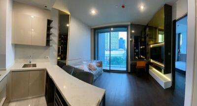 Modern open-concept living space with kitchen, living area, and a glimpse of the bedroom