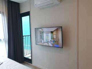Modern bedroom with wall-mounted TV and balcony access