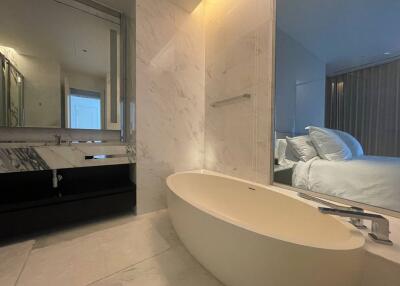 Modern bedroom with en-suite bathroom featuring a freestanding bathtub and marble finishes