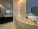 Modern bedroom with en-suite bathroom featuring a freestanding bathtub and marble finishes