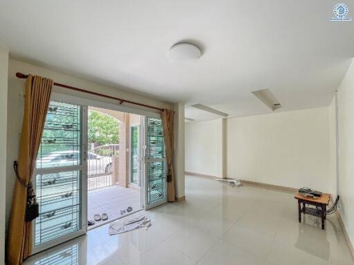 Spacious and well-lit living room with large windows and glass door leading to outdoor area