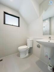 Compact modern bathroom with white tiles and natural light