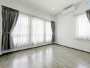 Spacious and bright empty living room with large windows and air conditioning unit