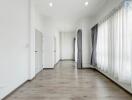 Spacious and well-lit empty room with hardwood floors and white walls