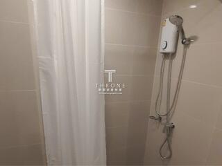 Compact bathroom with shower curtain and wall-mounted electric shower unit