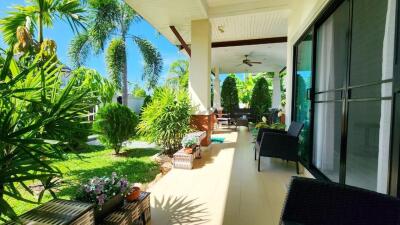 Spacious patio with lush garden view, comfortable seating and overhead fan