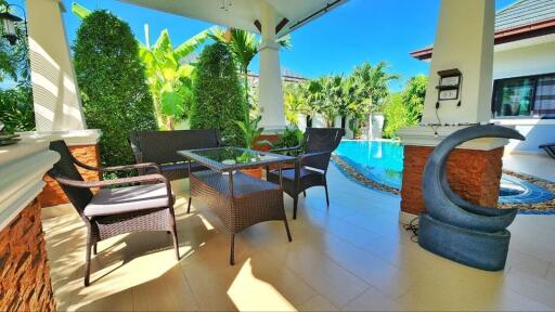 Spacious patio area with poolside view, outdoor furniture, and tropical plants