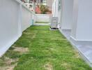 Narrow strip of outdoor grassy area with a pathway alongside a building