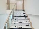 Modern staircase with marble-like steps and glass balustrade