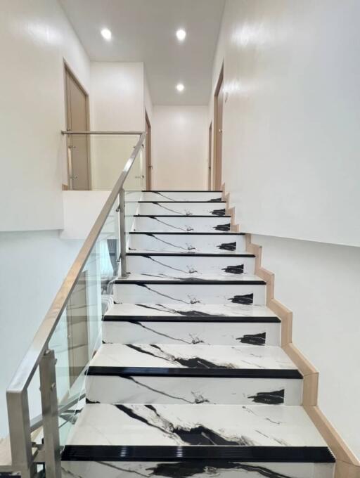 Modern staircase with marble-like steps and glass balustrade