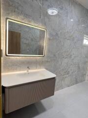 Modern bathroom with illuminated mirror and marble walls
