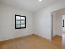 Empty bedroom with hardwood floors and white walls