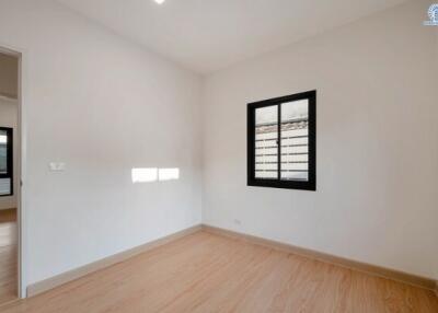 Spacious bedroom with wood flooring and natural light