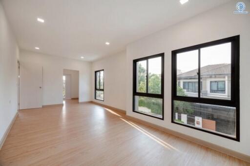 Spacious and well-lit empty living room with hardwood floors and large windows