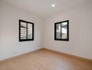 Spacious and well-lit empty bedroom with two windows