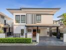 Modern two-story house with a flat roof, carport, and landscaped garden