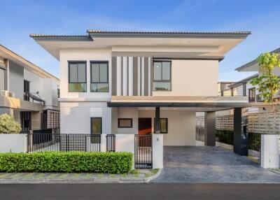 Modern two-story house with a flat roof, carport, and landscaped garden