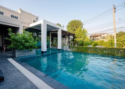 Luxurious outdoor swimming pool with surrounding greenery and adjacent building