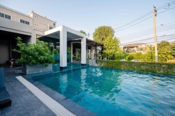 Luxurious outdoor swimming pool with surrounding greenery and adjacent building