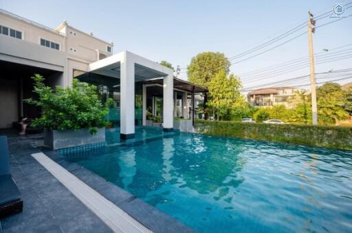 Luxurious outdoor swimming pool with surrounding greenery and adjacent building