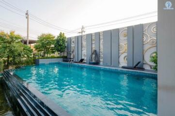 Swimming pool area with decorative wall and sun loungers