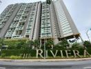 Exterior view of The Riviera residential building with lush landscaping