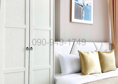 Cozy bedroom interior with white door, decorative pillows, and art on the wall