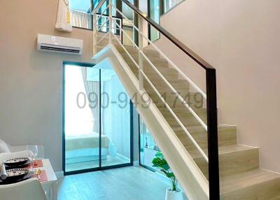 Bright living space with white walls and modern staircase leading to upper level