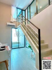 Bright living space with white walls and modern staircase leading to upper level