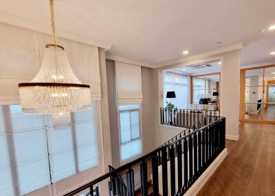 Spacious and well-lit upper floor living area with elegant chandelier and modern railings