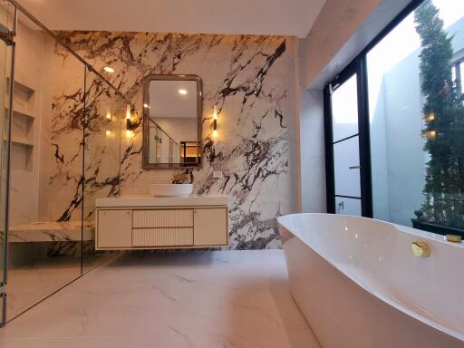 Luxurious bathroom with marble walls, freestanding tub, and large glass shower