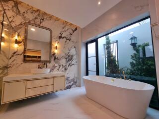 Spacious modern bathroom with freestanding bathtub and garden view