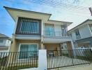 Modern two-story residential house with a balcony and carport