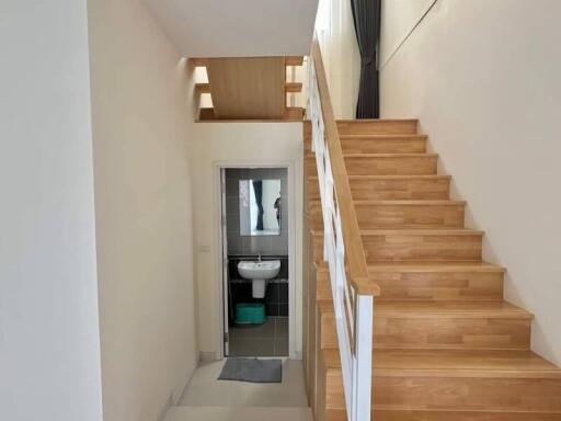 Wooden staircase with white railing leading to upper floor with a small bathroom visible underneath