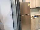Compact modern kitchen with stainless steel fridge and wooden cabinets