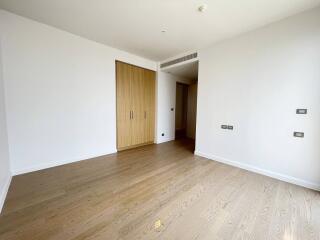 Spacious and naturally lit bedroom with wooden flooring and white walls