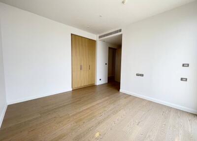 Spacious and naturally lit bedroom with wooden flooring and white walls