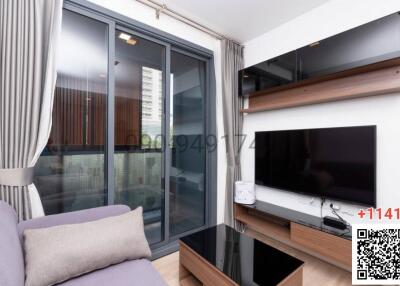 Modern living room with sliding doors to the balcony, featuring a flat-screen TV and a comfortable couch