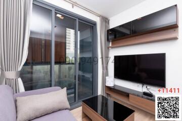 Modern living room with sliding doors to the balcony, featuring a flat-screen TV and a comfortable couch